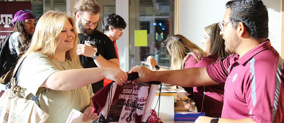 Female taking Engineering Academies swag from Texas A&M Staff